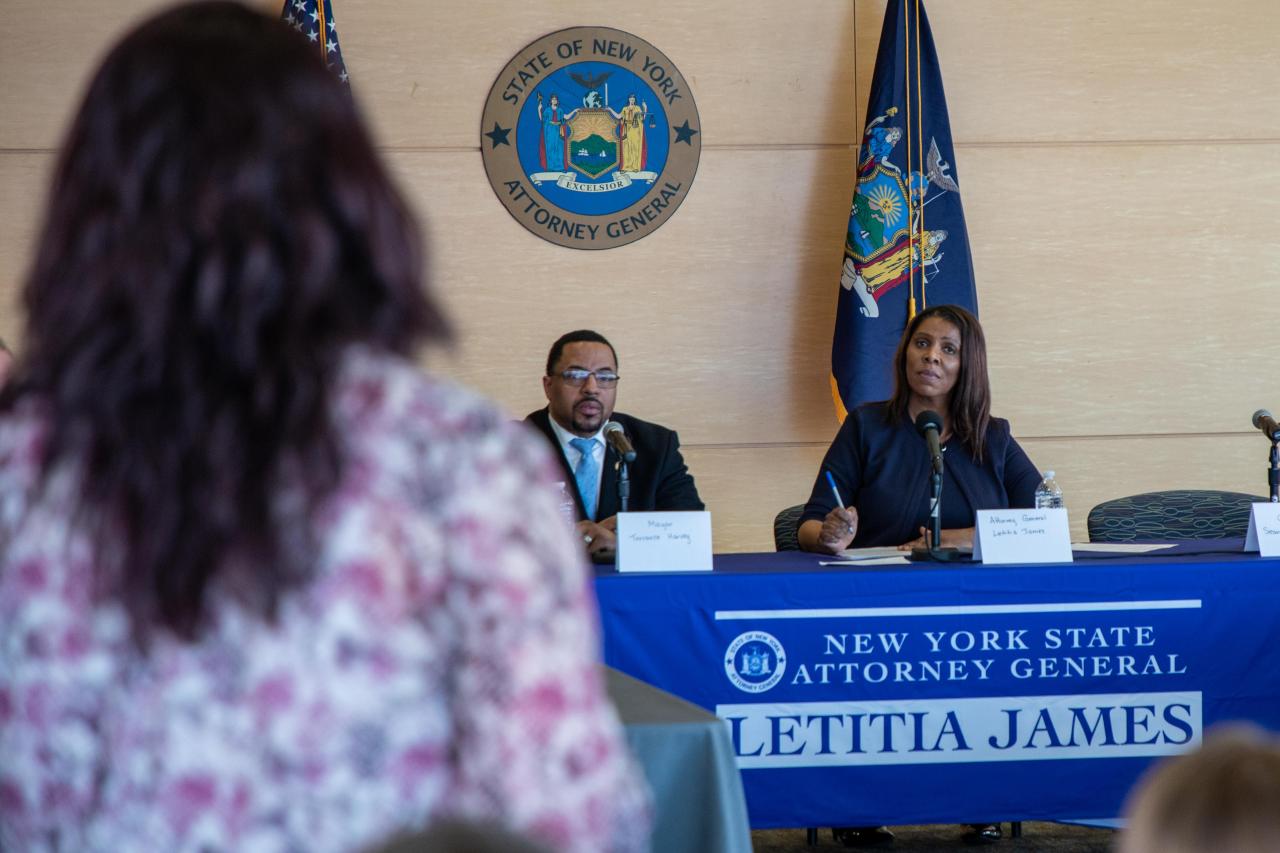 Attorney General James sits behind a table